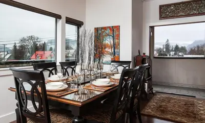 a dining room with a table and chairs and windows at Alpenglow Penthouse by Revelstoke Vacations in Revelstoke