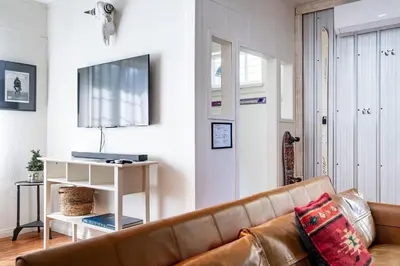 a living room with a brown couch and a television at The Downtown Hive by Revelstoke Vacations in Revelstoke