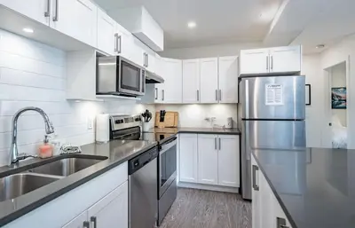 a kitchen with white cabinets and a stainless steel refrigerator at RendezView by Revelstoke Vacations in Revelstoke