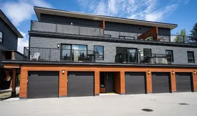 a building with four garage doors and a balcony at RendezView by Revelstoke Vacations in Revelstoke