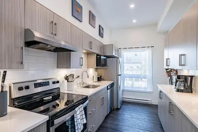 a kitchen with wooden cabinets and a stove top oven at Pillow Top Condo by Revelstoke Vacations in Revelstoke