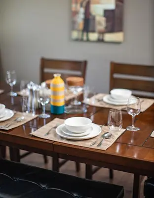 a wooden table with plates and wine glasses on it at Selkirk Snug by Revelstoke Vacations in Revelstoke