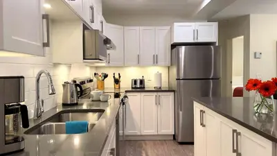 a kitchen with white cabinets and a stainless steel refrigerator at Al's Escape by Revelstoke Vacations in Revelstoke