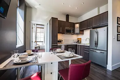 a kitchen with a table and chairs and a refrigerator at In the Heart of it All by Revelstoke Vacations in Revelstoke