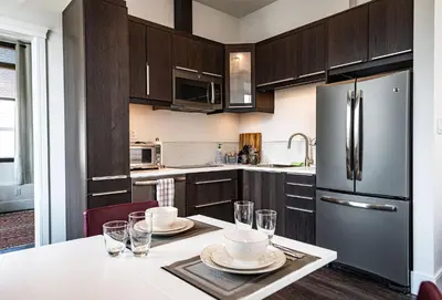 a kitchen with wooden cabinets and a stainless steel refrigerator at In the Heart of it All by Revelstoke Vacations in Revelstoke