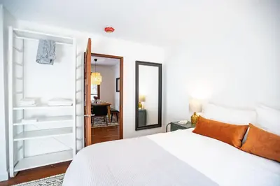 a white bedroom with a bed and a mirror at Mackenzie House by Revelstoke Vacations in Revelstoke
