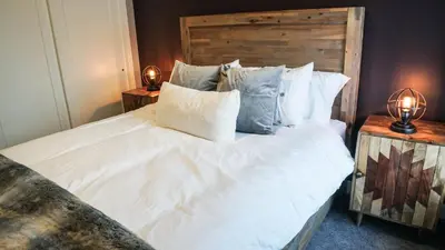 a bedroom with a large white bed with two lamps at The Revy Den by Revelstoke Vacations in Revelstoke