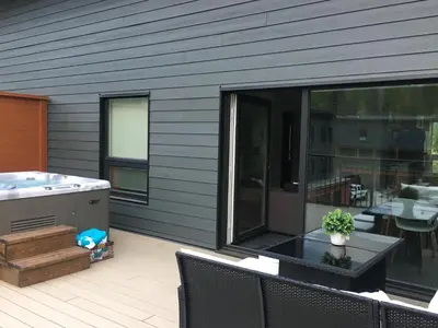 a patio with a hot tub and a table with chairs at The Revy Den by Revelstoke Vacations in Revelstoke