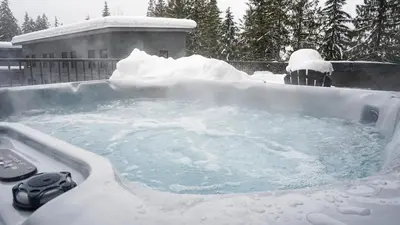 a hot tub covered in snow in front of a house at The Revy Den by Revelstoke Vacations in Revelstoke