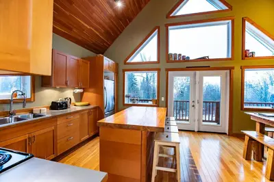 a large kitchen with wooden cabinets and windows at Stoke Cabin by Revelstoke Vacations in Revelstoke
