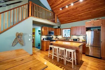 a kitchen with wooden cabinets and a kitchen island with bar stools at Stoke Cabin by Revelstoke Vacations in Revelstoke