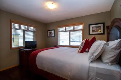 a bedroom with a large bed with two windows at Give Something Back Retreat by Revelstoke Vacations in Revelstoke
