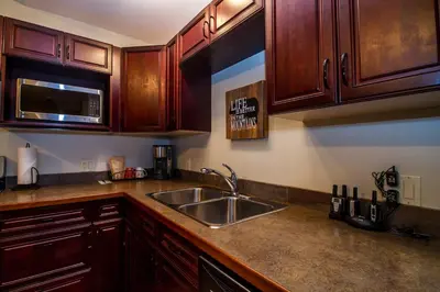a kitchen with wooden cabinets and a stainless steel sink at Give Something Back Retreat by Revelstoke Vacations in Revelstoke
