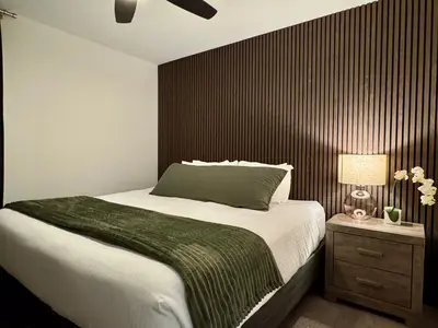 a bedroom with a large bed and a wooden wall at Granite Ridge Condo by Revelstoke Vacations in Revelstoke