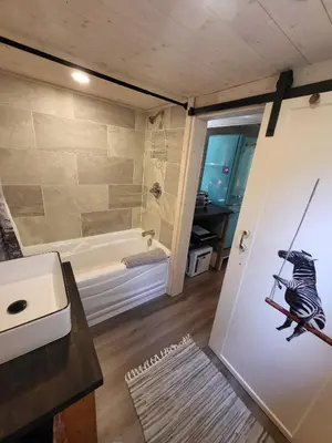 a bathroom with a tub and a door with a zebra on it at Forest Nook in Queens Bay