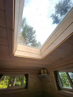 a skylight in a wooden house with two windows at Forest Nook in Queens Bay