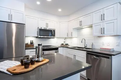 a kitchen with white cabinets and stainless steel appliances at Revelation Retreat by Revelstoke Vacations in Revelstoke