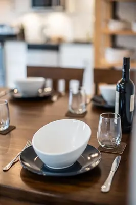 a wooden table with a bowl and a plate and a bottle of wine at Niska's Den by Revelstoke Vacations in Revelstoke