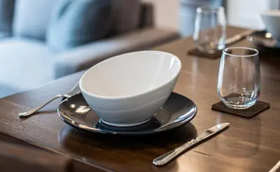 a bowl on a plate on a table with two glasses at Niska's Den by Revelstoke Vacations in Revelstoke