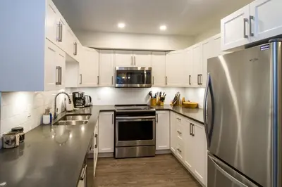 a kitchen with white cabinets and a stainless steel refrigerator at Magog Condo by Revelstoke Vacations in Revelstoke