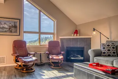 a living room with two chairs and a fireplace at Mountain getaway condo - 5 min walk to the beach! in Invermere