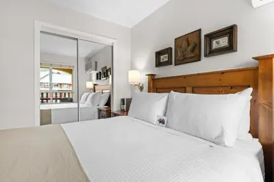 a bedroom with a white bed and a mirror at Bear Lodge One Bedroom by MVA in Whistler
