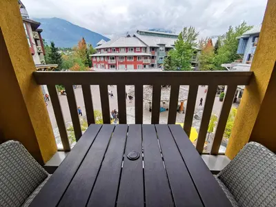 a wooden table on a balcony with a view at Bear Lodge One Bedroom by MVA in Whistler