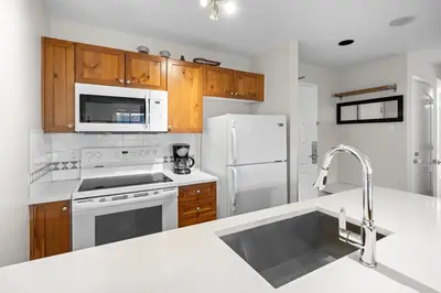 a kitchen with white appliances and wooden cabinets at Bear Lodge One Bedroom by MVA in Whistler