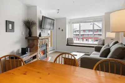 a living room with a couch and a table with a fireplace at Bear Lodge One Bedroom by MVA in Whistler