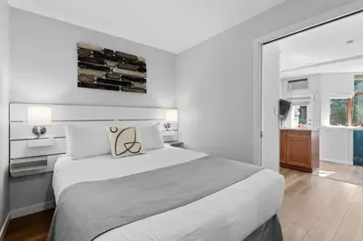 a white bedroom with a large bed and a window at Alpenglow Lodge Snooze Studio with Den by MVA in Whistler