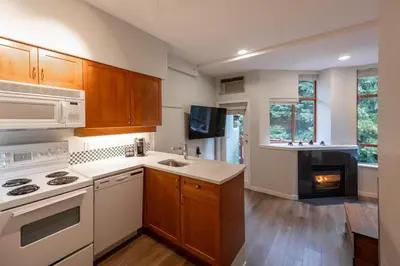 a kitchen with white appliances and wooden cabinets at Alpenglow Lodge Snooze Studio with Den by MVA in Whistler