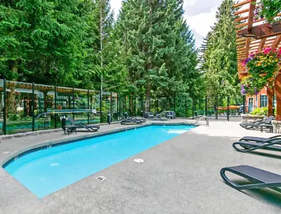 a swimming pool with lounge chairs and trees at Alpenglow Lodge Studio with Pool Views by MVA in Whistler