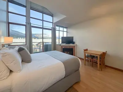 a bedroom with a bed and a desk with a television at Alpenglow Lodge Rainbow Look Out Studio by MVA in Whistler