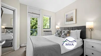 a bedroom with a king sized bed and a window at Alpenglow Lodge Two Bedroom Apartment by MVA in Whistler