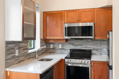 a kitchen with wooden cabinets and a stove and microwave at Alpenglow Lodge Two Bedroom Apartment by MVA in Whistler