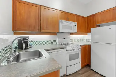 a kitchen with white appliances and wooden cabinets at Alpenglow Lodge Junior One Bedroom by MVA in Whistler