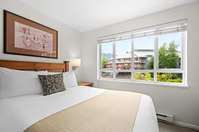 a white bedroom with a bed and a window at Bear Lodge Two Bedroom by MVA in Whistler