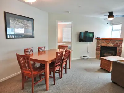 a dining room with a table and chairs and a fireplace at Bear Lodge Two Bedroom by MVA in Whistler