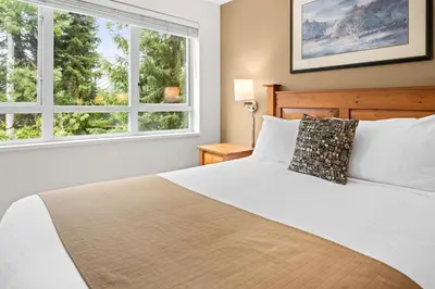 a bedroom with a bed and two windows at Bear Lodge Two Bedroom by MVA in Whistler