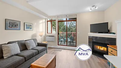 a living room with a couch and a fireplace at Alpenglow Lodge Studio with park view by MVA in Whistler