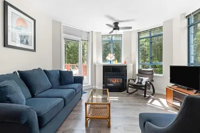 a living room with a blue couch and a fireplace at Alpenglow Lodge Bear Wonder One Bedroom by MVA in Whistler