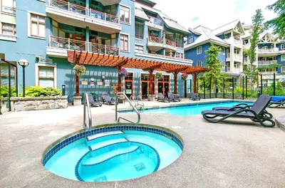a swimming pool with two chairs and a building at Alpenglow Lodge Family Studio with Murphy Bed by MVA in Whistler