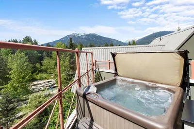 a hot tub on a balcony with mountains in the background at Alpenglow Lodge Two Bedroom Apartment with Private Hot Tub by MVA in Whistler