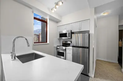 a white kitchen with a sink and a refrigerator at Alpenglow Lodge Two Bedroom Apartment with Private Hot Tub by MVA in Whistler
