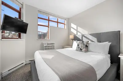 a bedroom with a large bed and a flat screen tv at Alpenglow Lodge Two Bedroom Apartment with Private Hot Tub by MVA in Whistler