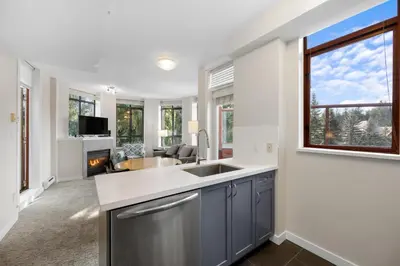 a kitchen with a sink and a fireplace at Alpenglow Lodge Two Bedroom Apartment with Private Hot Tub by MVA in Whistler