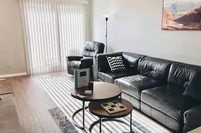 a living room with a black leather couch and a table at Spacious 2-bedroom apartment in Camrose