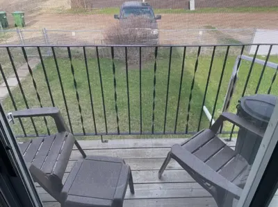 a balcony with two chairs and a car in a parking lot at Spacious 2-bedroom apartment in Camrose