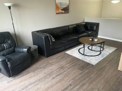 a living room with a black leather couch and a table at Spacious 2-bedroom apartment in Camrose