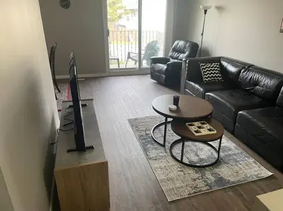 a living room with a black couch and a table at Spacious 2-bedroom apartment in Camrose